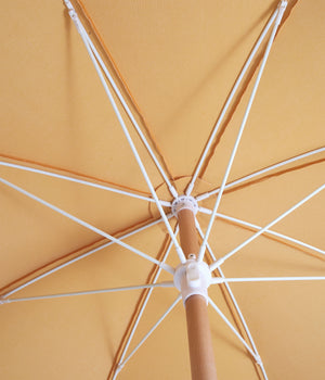 Sunday Supply Co Golden beach umbrella open and seen from underneath.